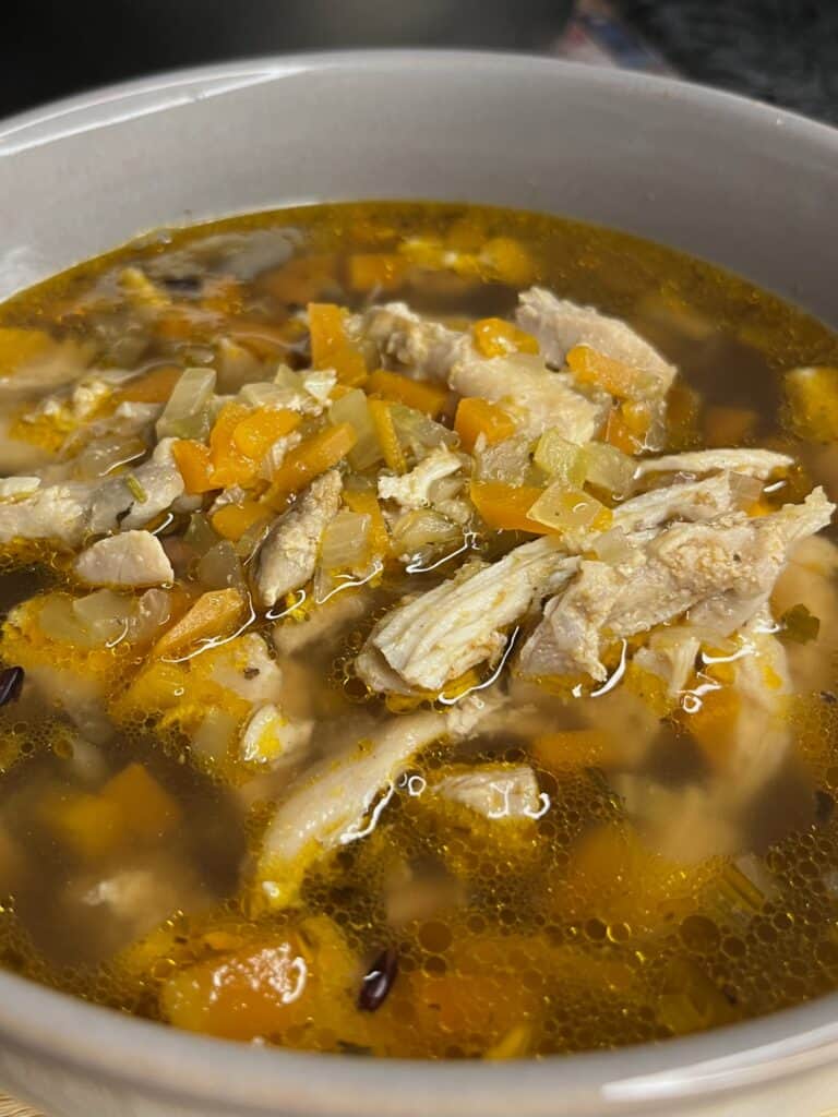 fresh chicken soup broth with chicken thighs, carrot, onion, celery, and chicken stock