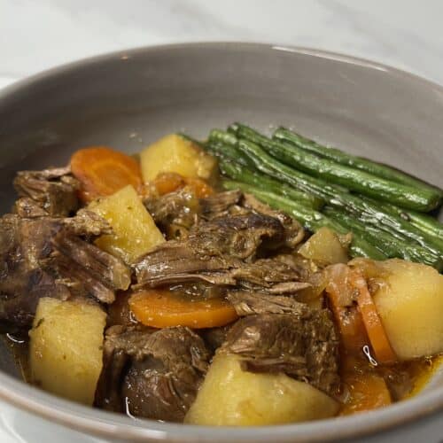 slow cooked pot roast with shredded beef, potatoes, carrot, in a rich gravy and a side of green beans