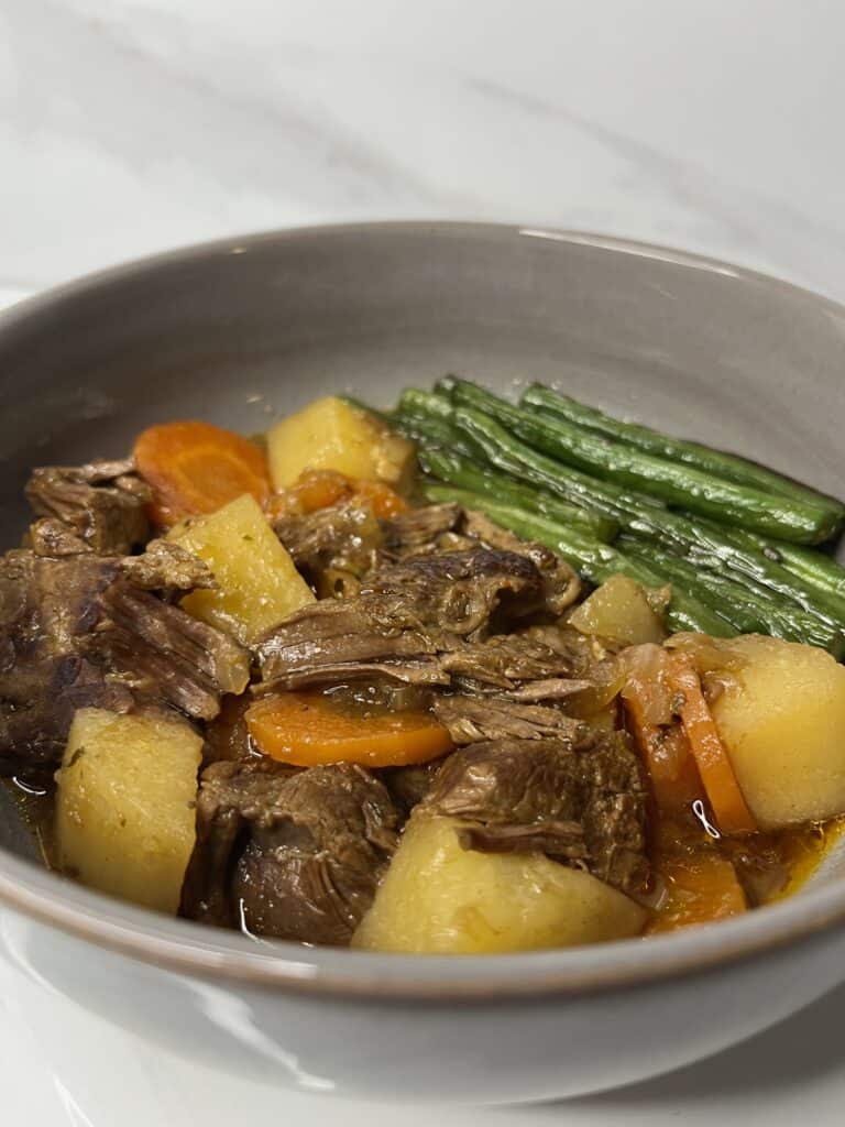 slow cooked pot roast with shredded beef, potatoes, carrot, in a rich gravy and a side of green beans