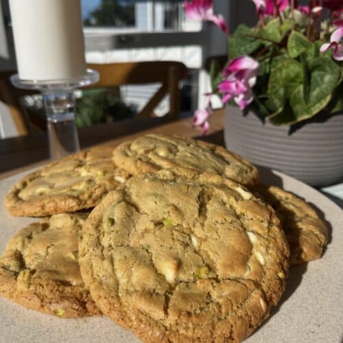 white chocolate pistachio cookies. gluten free, multiple cookies laid on top of each other in the sun