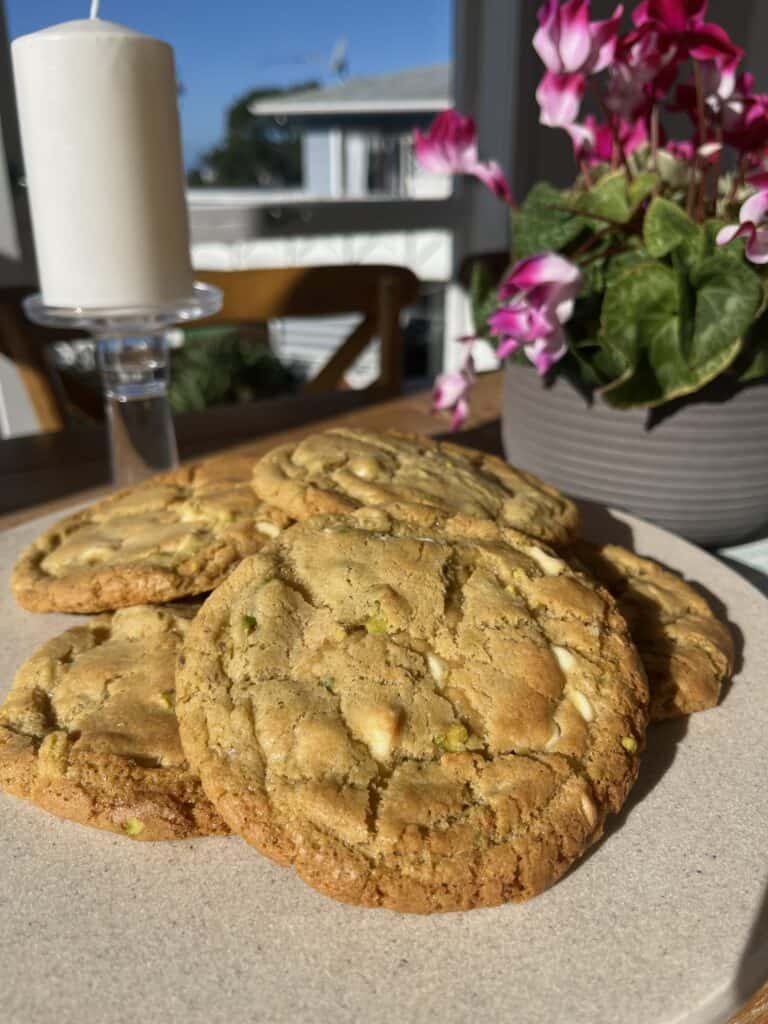 white chocolate pistachio cookies. gluten free, multiple cookies laid on top of each other in the sun