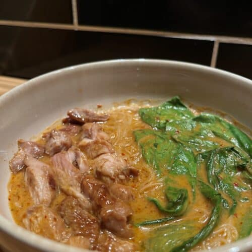 thai red curry soup, red curry paste and chicken broth with chicken thighs and bok choy