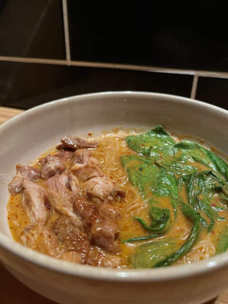 thai red curry soup, red curry paste and chicken broth with chicken thighs and bok choy