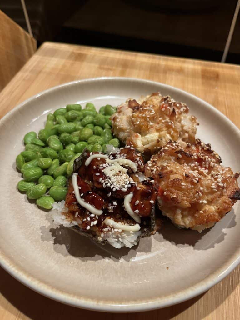 sushi bake in muffin form with nori seaweed. topped with teriyaki chicken, and a cream cheese seafood mix. prawns, shrimp, surimi crab. edamame beans on the side