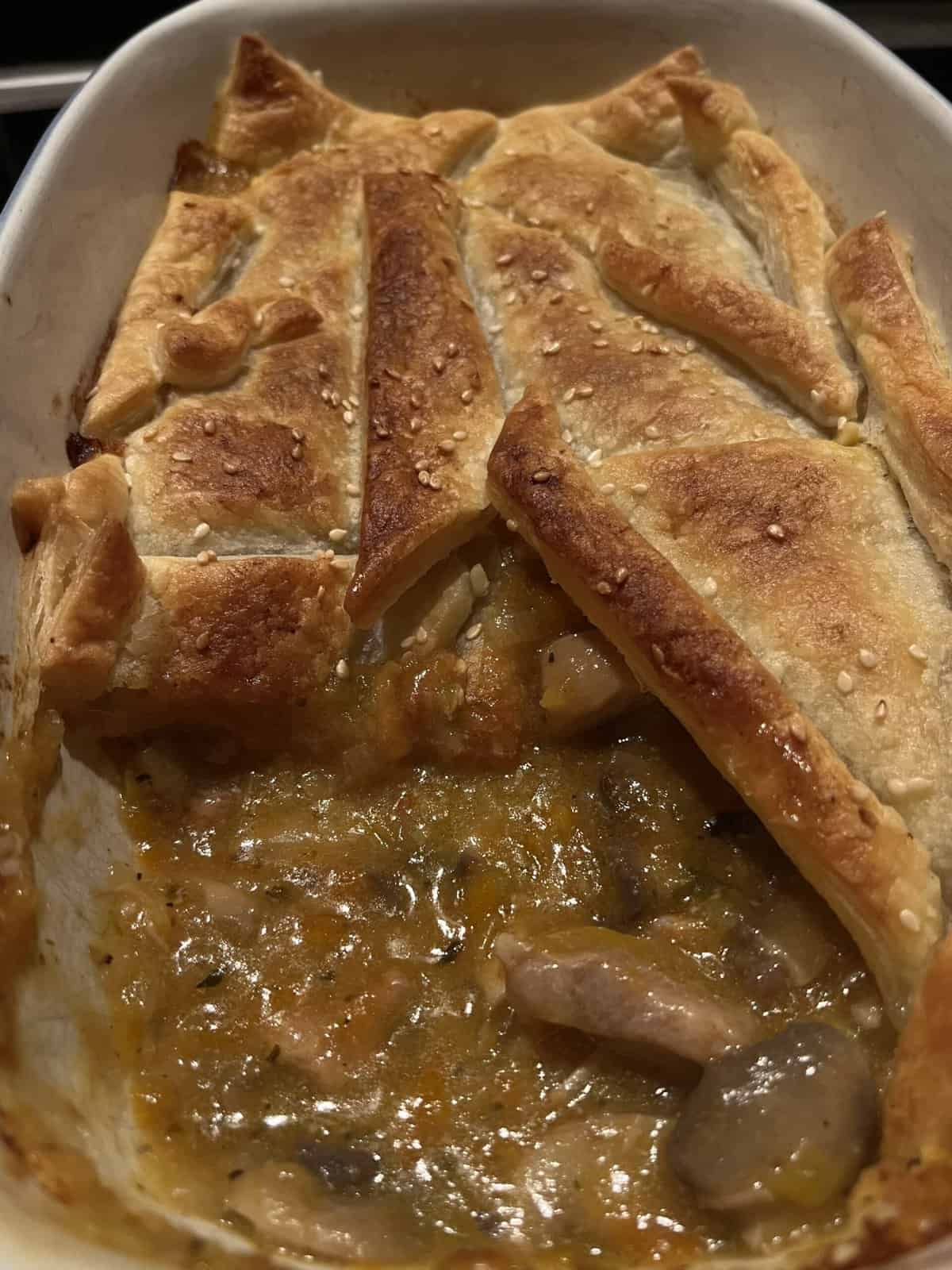 hot chicken, leek, and mushroom pie with a rich thick gravy in an oven safe dish with puff pastry