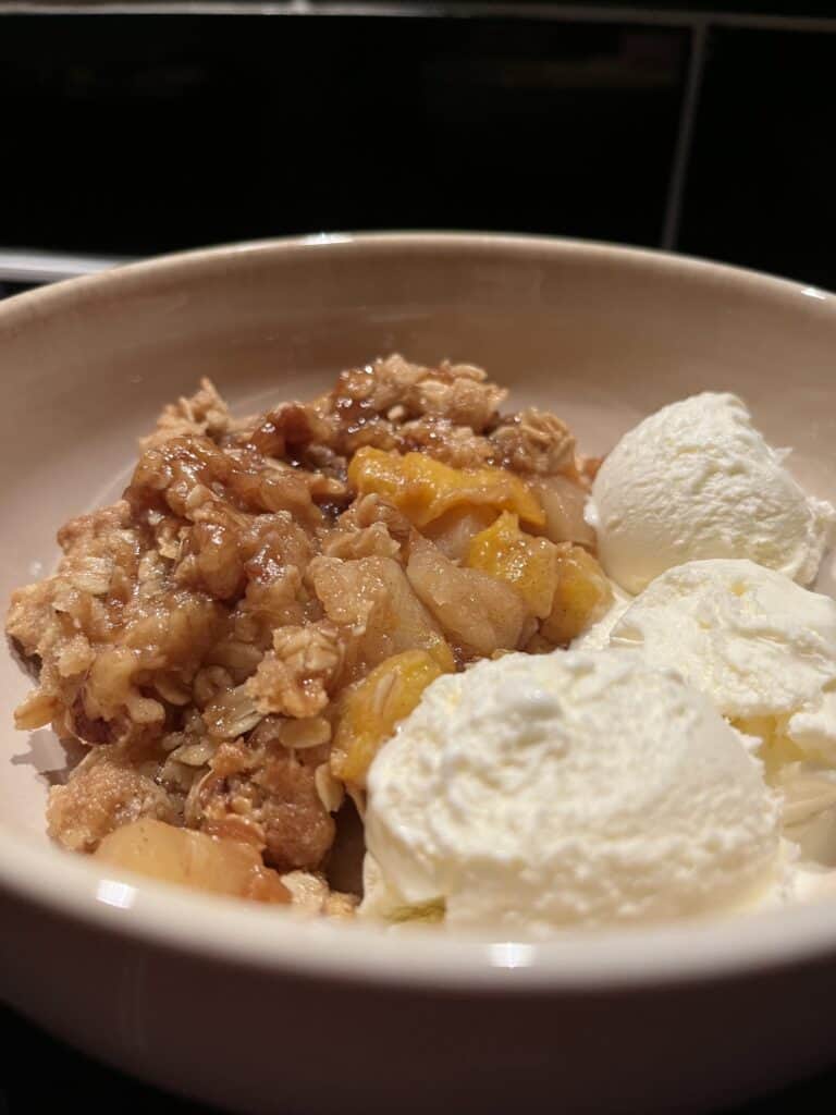 peach and apple crumble with oat and walnut topping, served warm with vanilla ice cream