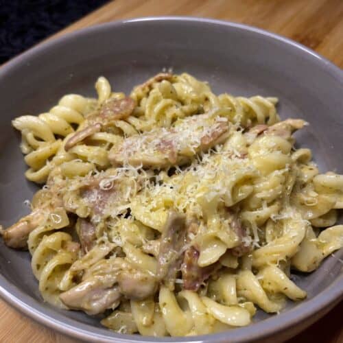 chicken bacon pesto pasta in a bowl topped with parmesan cheese