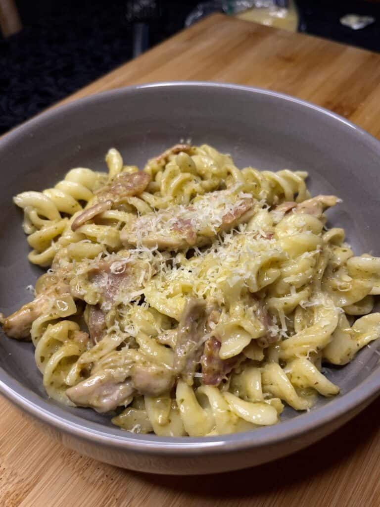 chicken bacon pesto pasta in a bowl topped with parmesan cheese