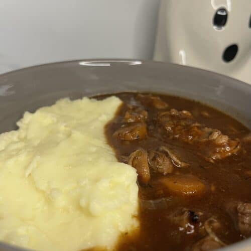 red wine chicken stew with chicken thighs, carrot, onion. served with creamy and cheesy mashed potatoes