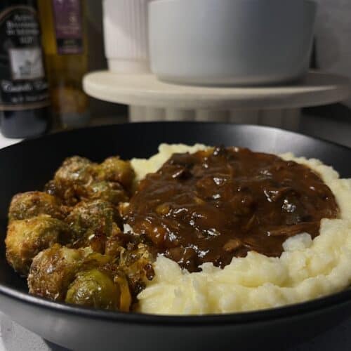 slow cooked beef bourguignon red wine stew on cheesy mashed potatoes and parmesan roasted brussel sprouts