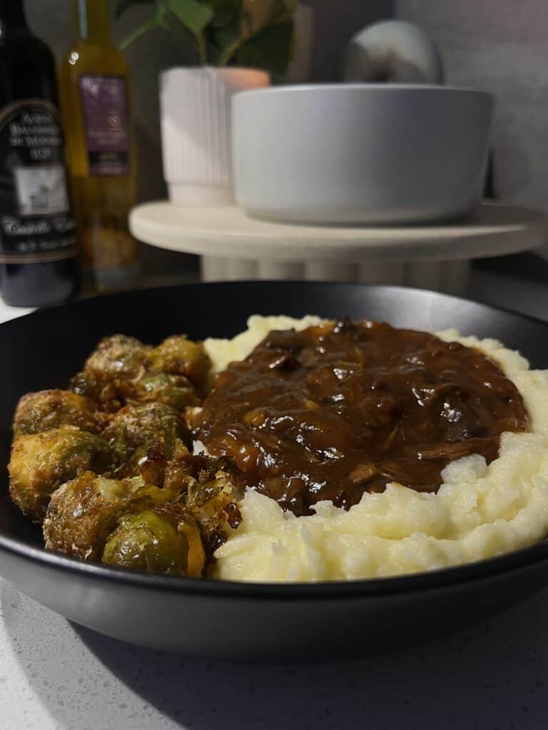 slow cooked beef bourguignon red wine stew on cheesy mashed potatoes and parmesan roasted brussel sprouts