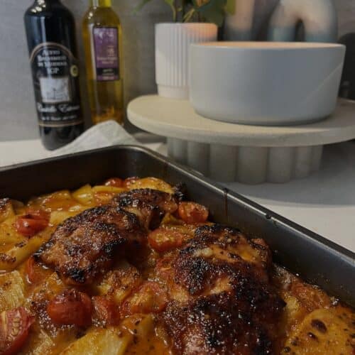 mediterranean chicken bake, chicken thighs, potato, onion, cherry tomatoes in a lime, olive oil, garlic, and honey sauce