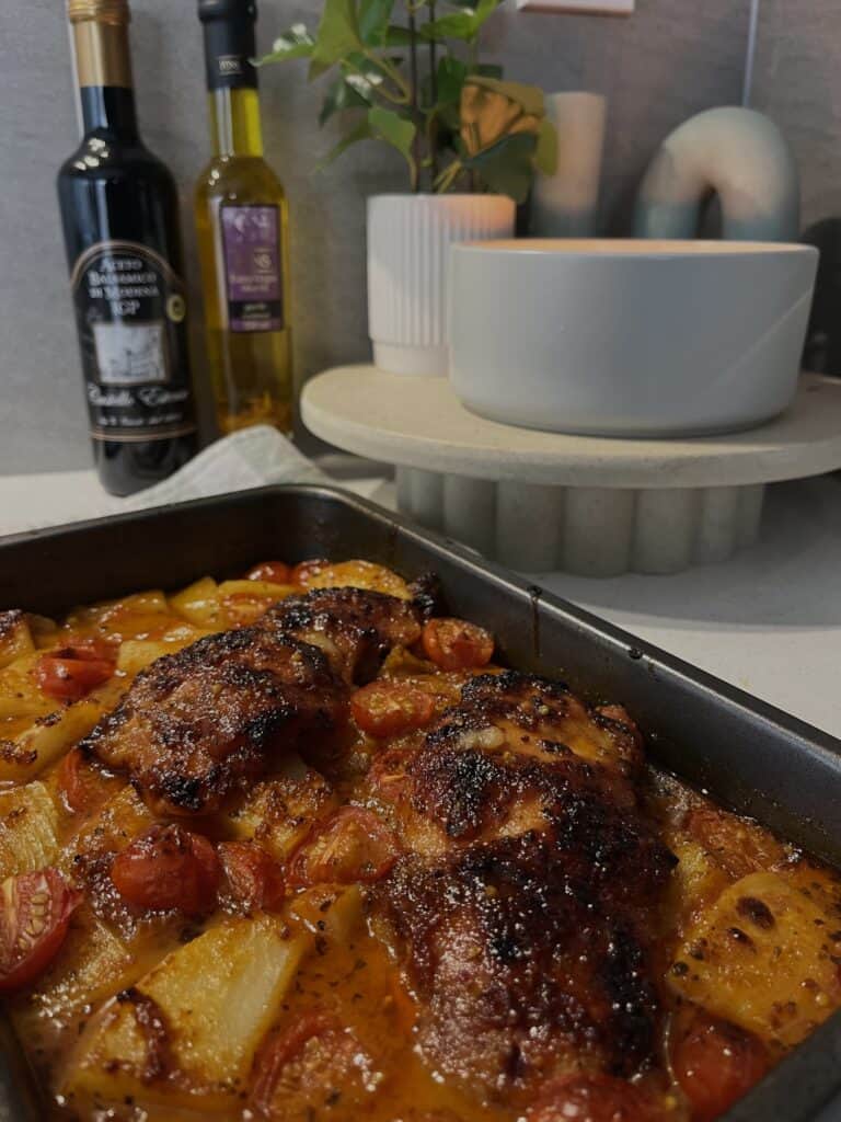 mediterranean chicken bake, chicken thighs, potato, onion, cherry tomatoes in a lime, olive oil, garlic, and honey sauce