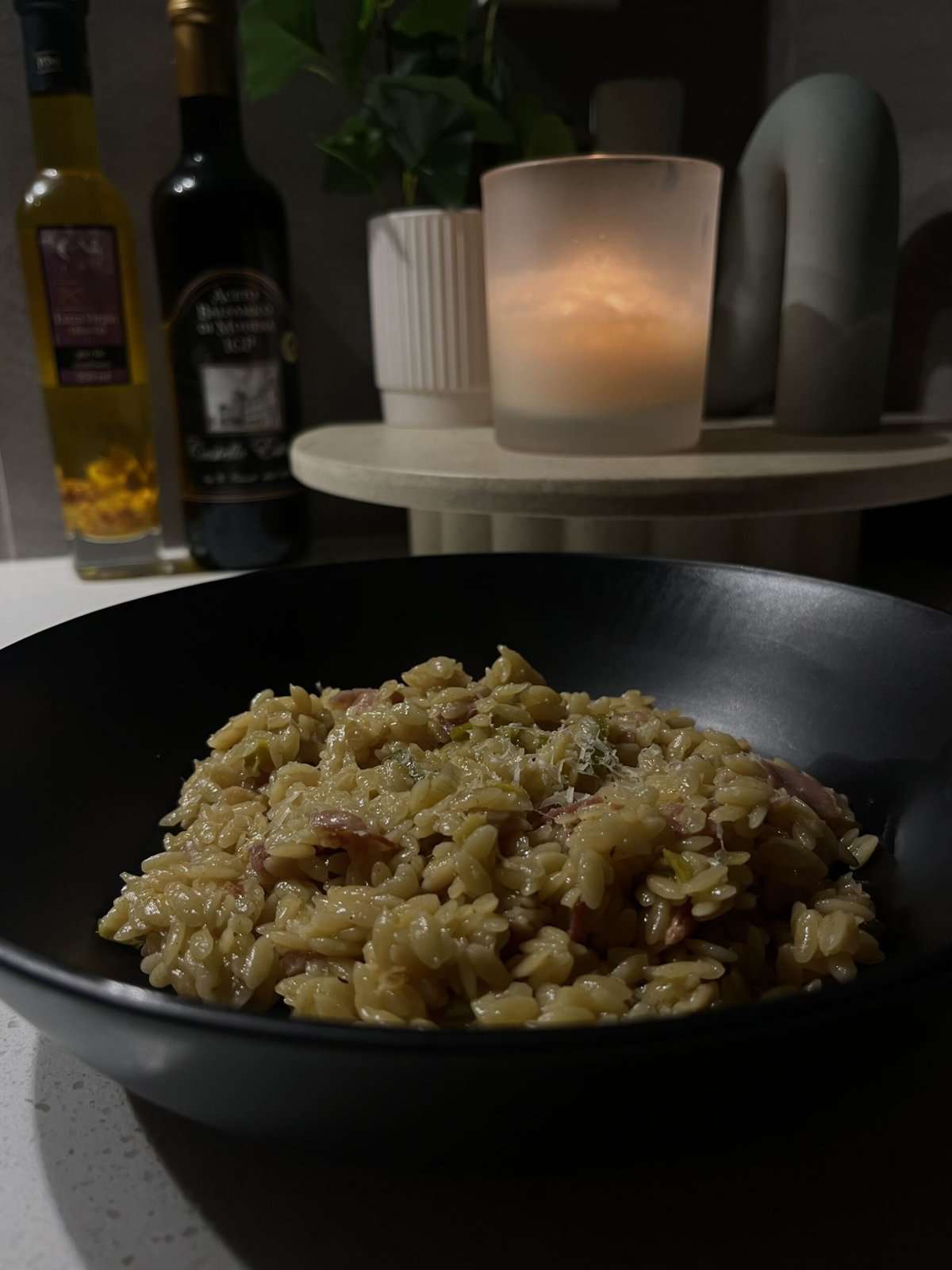 leek and bacon orzo in a black bowl with a parmesan sauce